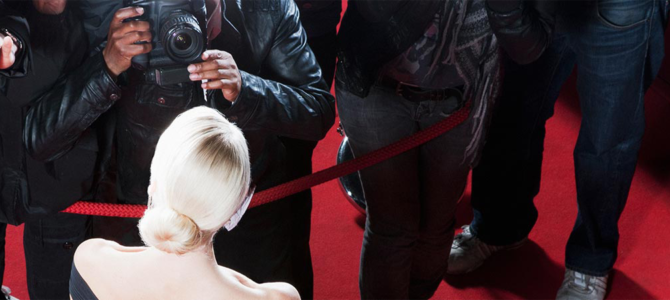 Photographers on the red carpet taking pictures of a blonde woman.