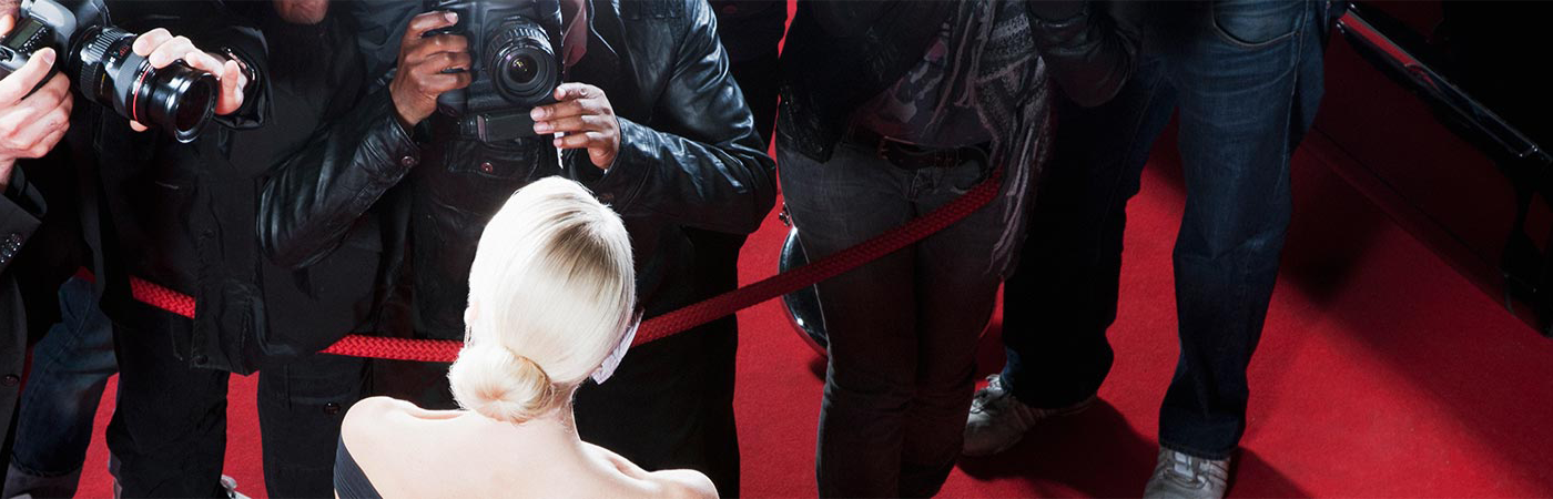 Photographers on the red carpet taking pictures of a blonde woman.